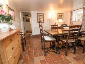 A dining room with a wooden table and chairs a sideboard with flowers and a lamp at The Cottage Halkyn near Holywell