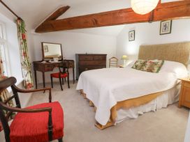 A bedroom with a bed dresser vanity mirror and red chairs at The Cottage in Halkyn near Holywell