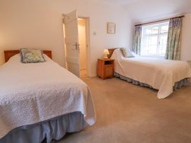 A bedroom with two single beds nightstand and lamp near a window with curtains at The Cottage in Halkyn near Holywell