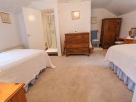 A bedroom with two beds a wooden dresser a chair a wooden wardrobe and an en suite bathroom at The Cottage Halkyn near Holywell