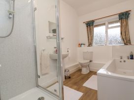 A bathroom with a shower, sink, toilet, bathtub, and window with curtains at The Cottage in Halkyn near Holywell