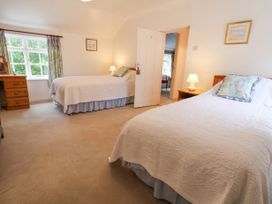 A bedroom with two single beds bedside tables lamps a dresser and a window with curtains at The Cottage in Halkyn near Holywell