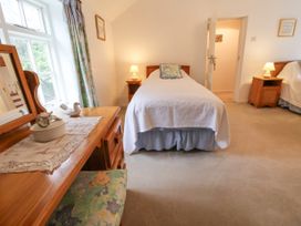 A bedroom with two single beds wooden bedside tables with lamps and a wooden dressing table with a mirror at The Cottage in Halkyn near Holywell