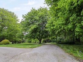 A gravel driveway surrounded by green trees and grass at The Cottage in Halkyn near Holywell