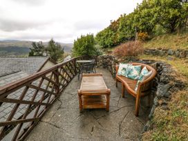 An outdoor patio area with wooden bench and table seating surrounded by stone walls and greenery at Y Stabal in Llanddoged near Llanrwst