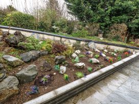 A garden bed with rocks and small plants next to a stone tiled pathway at Y Stabal in Llanddoged near Llanrwst