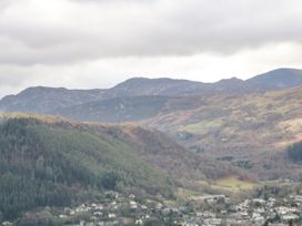 A view of a valley with houses below hills covered with trees and mountains in the background at Y Stabal in Llanddoged near Llanrwst