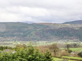 A rural landscape with trees fields houses and hills under a cloudy sky at Y Stabal in Llanddoged near Llanrwst