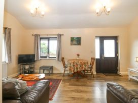 A living room with brown leather sofas a wooden table a small dining table with chairs and a TV at Y Stabal in Llanddoged near Llanrwst