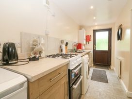 A kitchen with countertop appliances stove and washing machine by a back door at Y Stabal in Llanddoged near Llanrwst