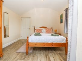 A bedroom with a wooden bed and nightstand with a lamp and clock at Y Stabal in Llanddoged near Llanrwst