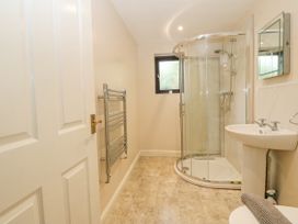 A bathroom with a corner shower, pedestal sink, wall mirror, towel radiator, and frosted window at Y Stabal in Llanddoged near Llanrwst