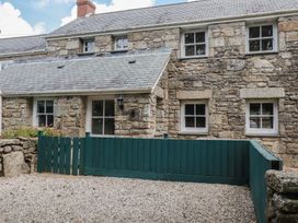 A stone house with windows and a green fence at 15 Boscaswell Downs in Pendeen