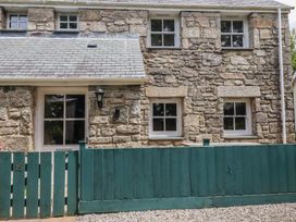 An exterior view of a stone cottage with a green fence at 15 Boscaswell Downs Pendeen