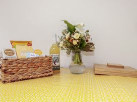 A kitchen table with a basket of snacks and a vase of flowers at 15 Boscaswell Downs Pendeen