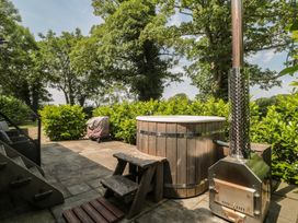 A hot tub and wooden bench with stove in the garden at Acorn in Bleadon