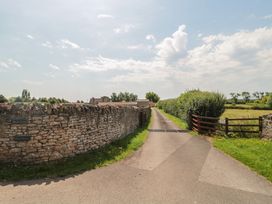 A dirt road with stone walls and a gate at Acorn in Bleadon
