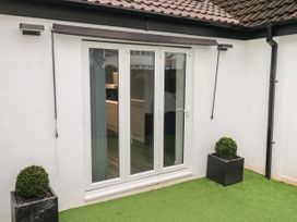 A set of white double glass doors leading to an indoor space with two potted plants on artificial grass at Sunnydene in Paignton