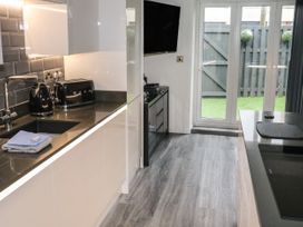 A modern kitchen with black countertop appliances a sink and glass doors leading to a garden at Sunnydene in Paignton