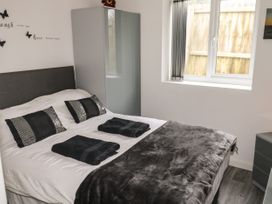 A bedroom with a bed dressed with black and white bedding two folded black towels on the bed a wardrobe near the window at Sunnydene in Paignton