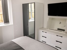 A bedroom with a bed, a wardrobe with mirrored doors, a dresser with a mirror, and a wall-mounted TV at Sunnydene in Paignton