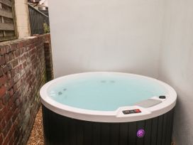 An outdoor hot tub surrounded by brick and white walls at Sunnydene in Paignton