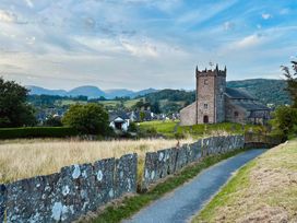 A church with a tower and pathway at Curlew Cottage at Hawkshead