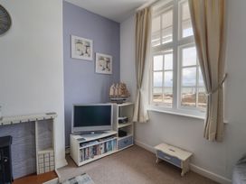A living room with a television, shelves, and a model ship at Flat F in 