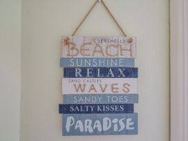 A decorative sign with beach-related phrases at Flat F in 