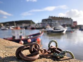 A chain on a pier with boats and buildings in the background at Flat F