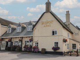 A pub building with flower baskets and barrels at Bridport Arms in West Bay