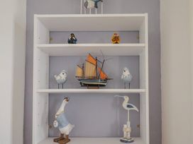 A shelf with decorative items including a boat and bird figurines at Flat F Bay House in West Bay