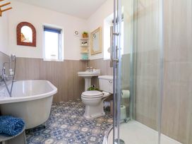 A bathroom with a bathtub, toilet, sink and shower at Postman's Cottage in Bridlington