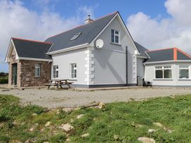 A house with a satellite dish and gravel area at Tí Tom Nárta in Trabane near Lettermore, County Galway