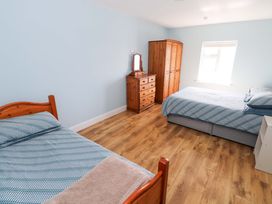 A bedroom with two beds and wooden furniture at Tí Tom Nárta, Trabane near Lettermore, County Galway