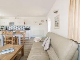A living room with a sofa and dining area at Owls Roost in Gorran Haven