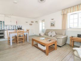 A living room with a sofa and dining table at Owls Roost in Gorran Haven