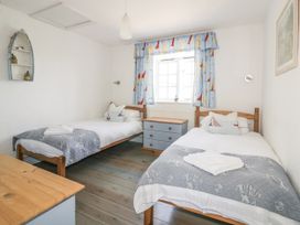 A bedroom with two single beds and a window at Owls Roost in Gorran Haven