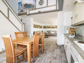 A dining room with table and chairs and a view of the kitchen at Squirrels Dray in Gorran Haven
