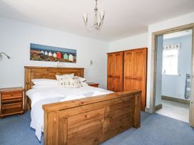 A bedroom with a bed and wardrobes at Squirrels Dray in Gorran Haven