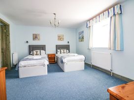 A bedroom with two beds and a nightstand at Squirrels Dray in Gorran Haven
