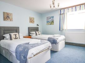 A bedroom with two beds and paintings on the wall at Squirrels Dray in Gorran Haven