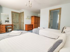 A bedroom with two beds and wooden furniture at Squirrels Dray in Gorran Haven