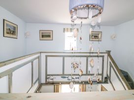 A hallway with a chandelier and framed paintings at Squirrels Dray in Gorran Haven