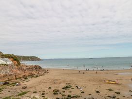 A beach with people and boats at Foxes Den in Gorran Haven