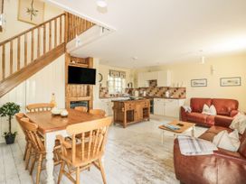 A living room with a table and chairs next to a kitchen at Foxes Den in Gorran Haven