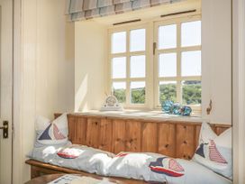 A snug area with a wooden bench and cushions at Foxes Den in Gorran Haven