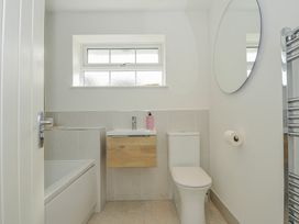A bathroom featuring a bath tub, toilet, sink and mirror at Samphire in Rock