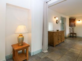 A hallway with a lamp, clock, table and chair at No 2 The Stables Capel Coch near Llannerch-Y-Medd