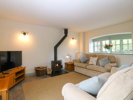 A living room with a wood stove and sofa at No 2 The Stables in Capel Coch near Llannerch-Y-Medd